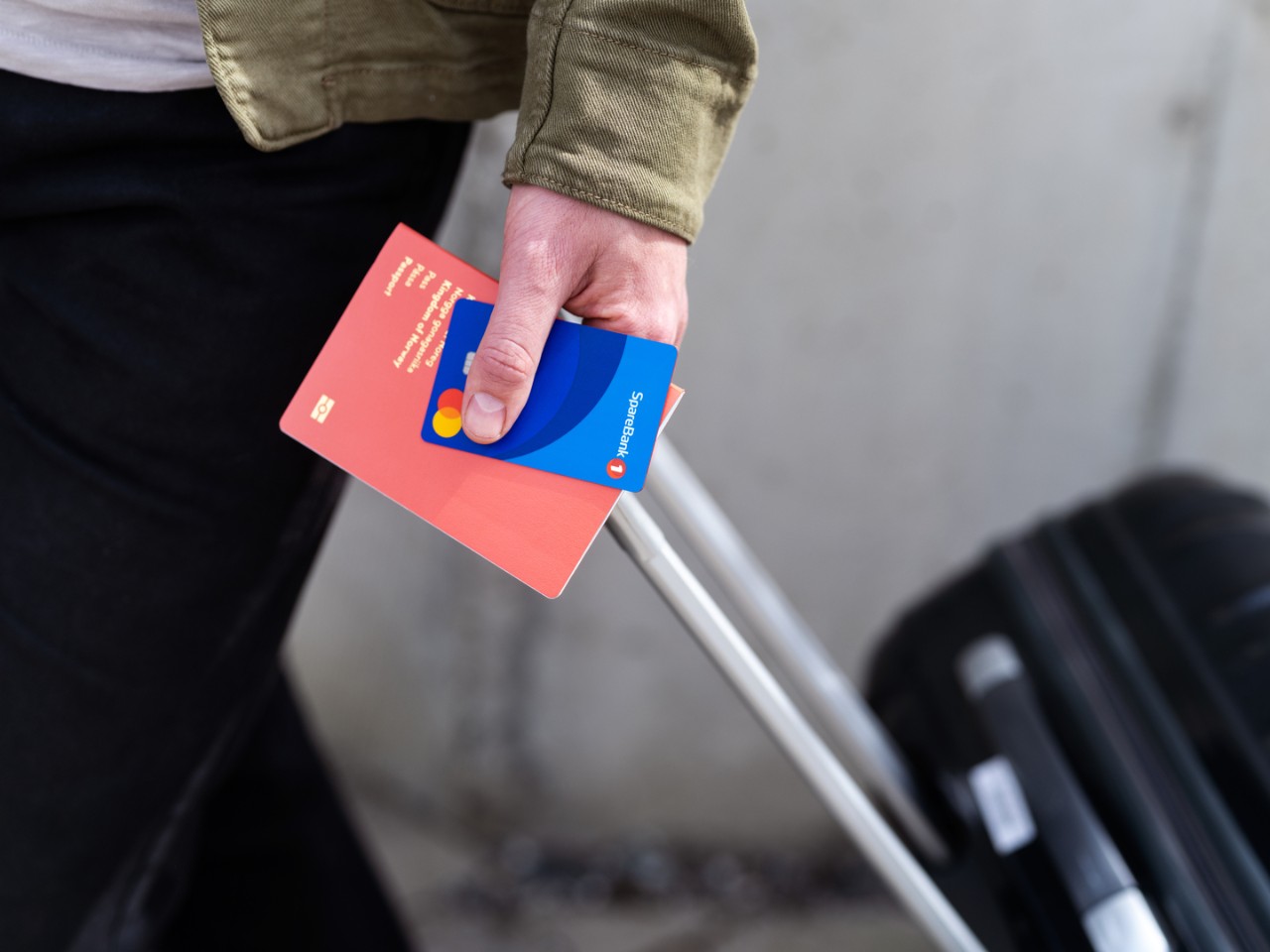 Hånd som holder kredittkort, pass og koffert