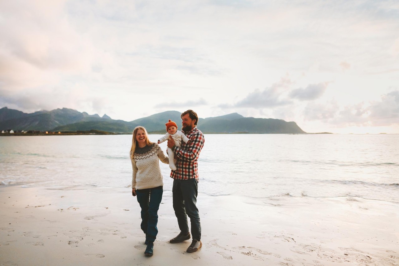 Family walking on beach vacation couple traveling with baby outdoor healthy lifestyle activity man and woman parents with child summer trip in Norway
