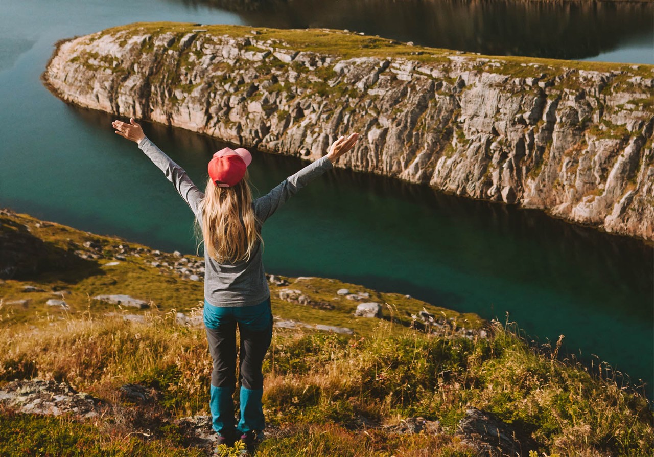 Woman adventurer raised hands traveling in Norway mountains rocks and sea view adventure vacations healthy lifestyle success motivation Helgeland islands landscape