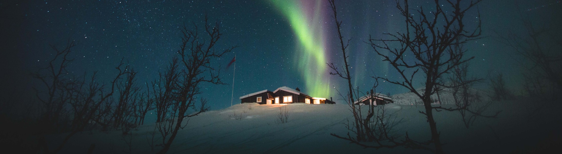 Beautiful Northern lights in the night sky above a lone cabin in Riksgransen, Sweden.