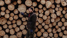Skogsägare står vid timmerstockar