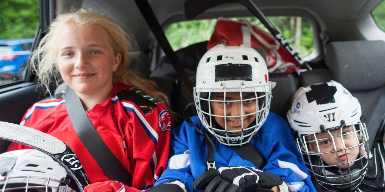 Barn med hockeyutstyr i baksete på bil