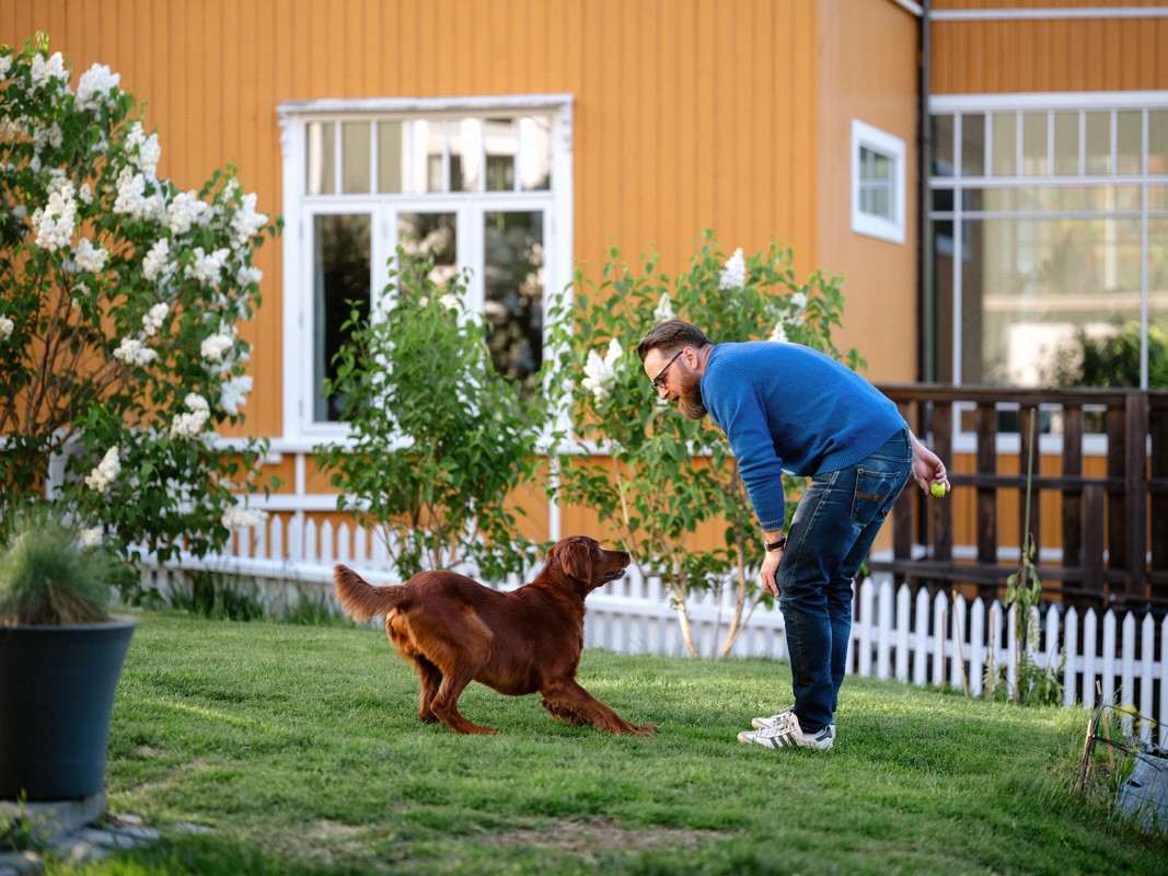 mann leiker med hund i hagen