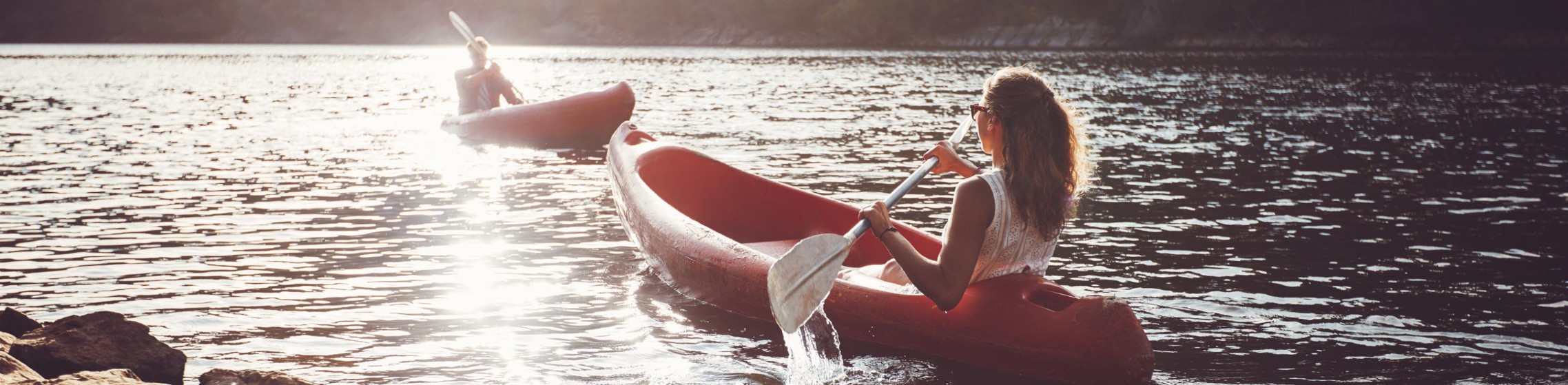 Young people kayaking in a lake. Young man and woman paddling kayaks on a sunny day.