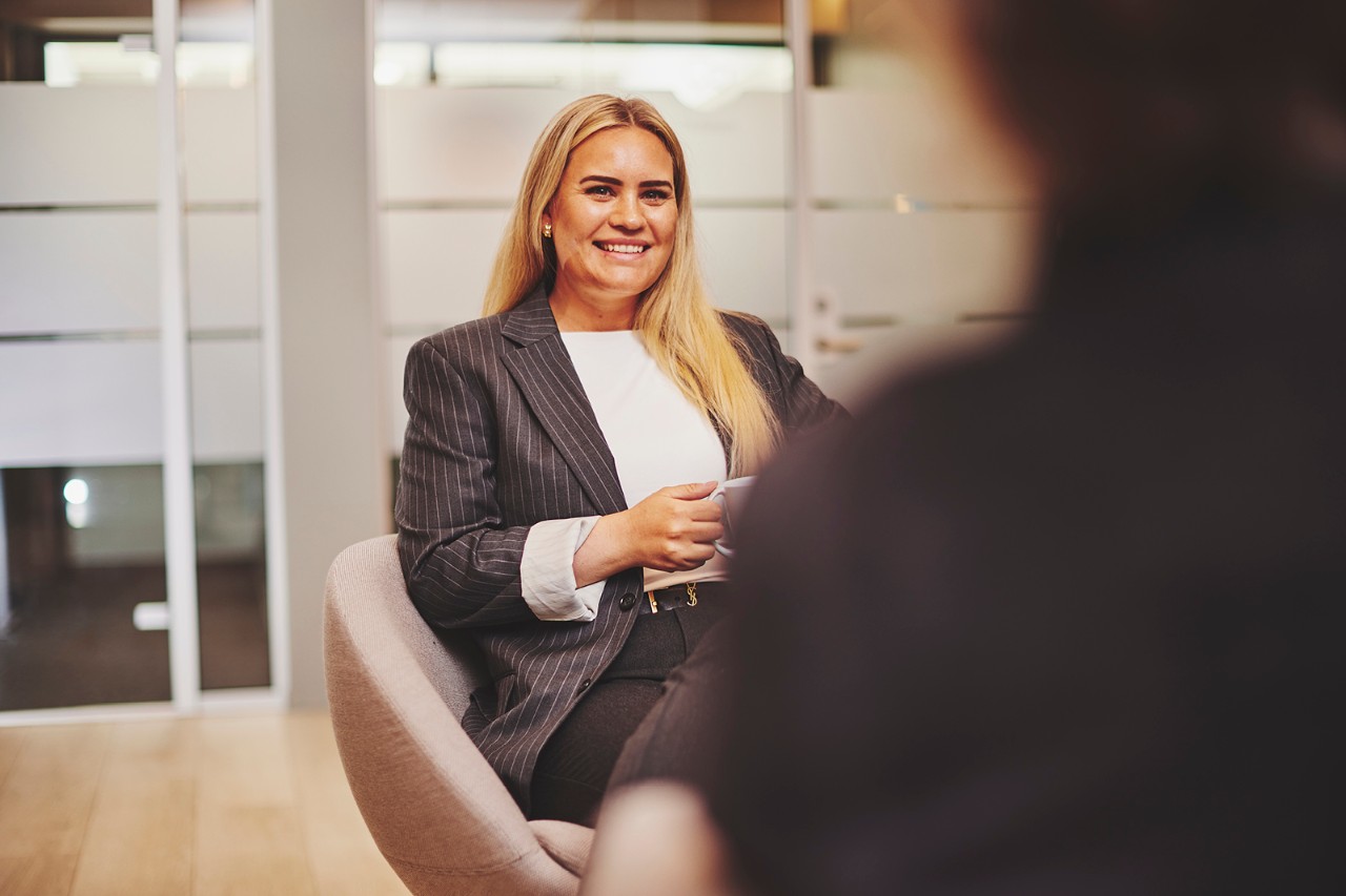 Dame sitter og smiler. Bilde.