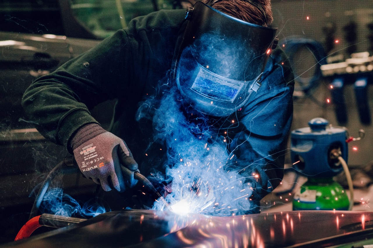 Mann som sveiser på verksted.