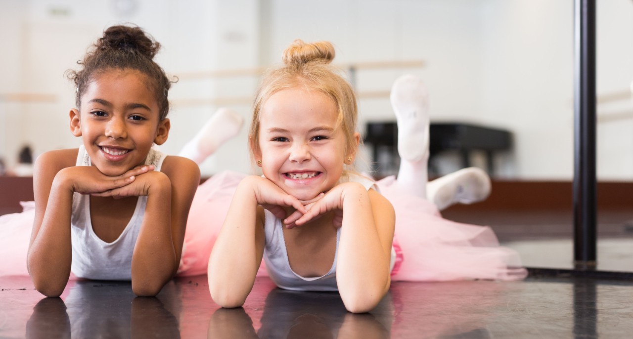 Two little girls in tutu rehearsing in classical dance school