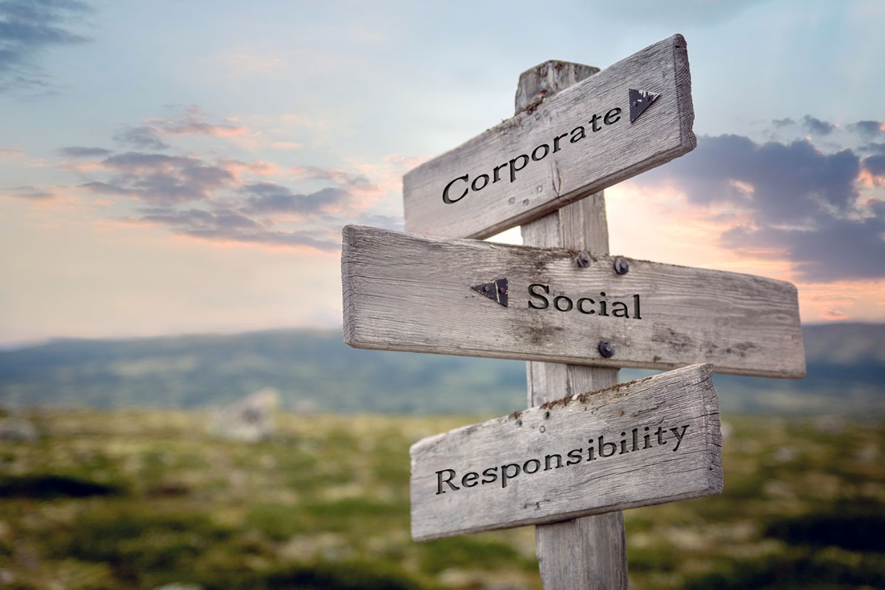 corporate social responsibility text quote on wooden signpost outdoors during sunset.