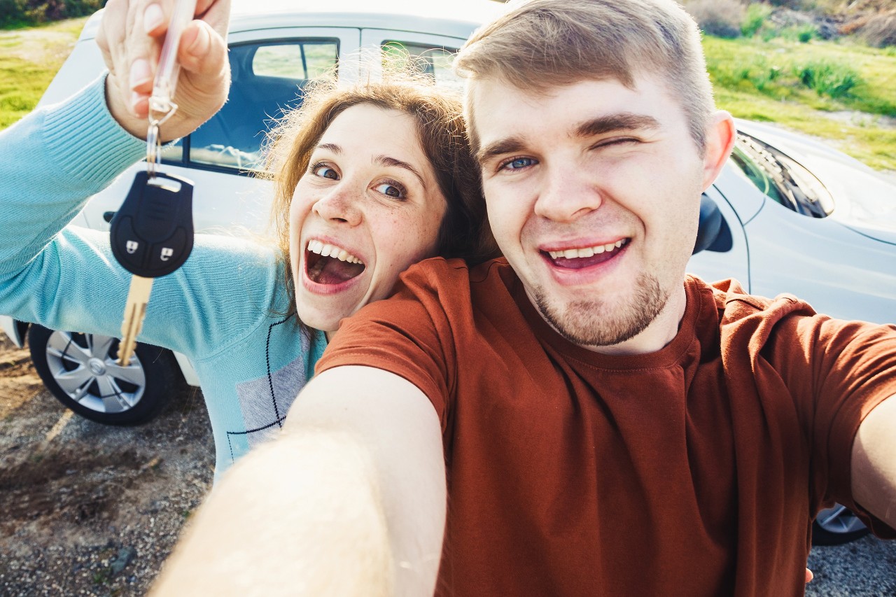 jente som har lånt bort bilen sin med bilforsikring til glad gutt som velger å fange øyeblikket med en selfie