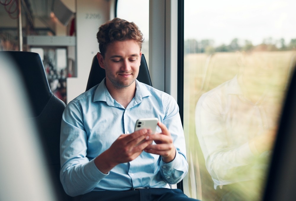 Mann ser på mobilen ombord i et tog.