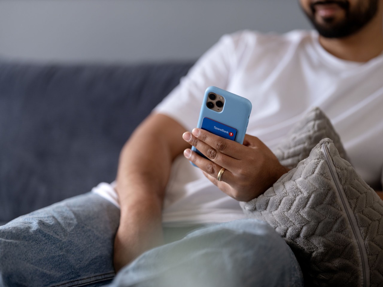 Mann i sofa med mobil og kredittkort