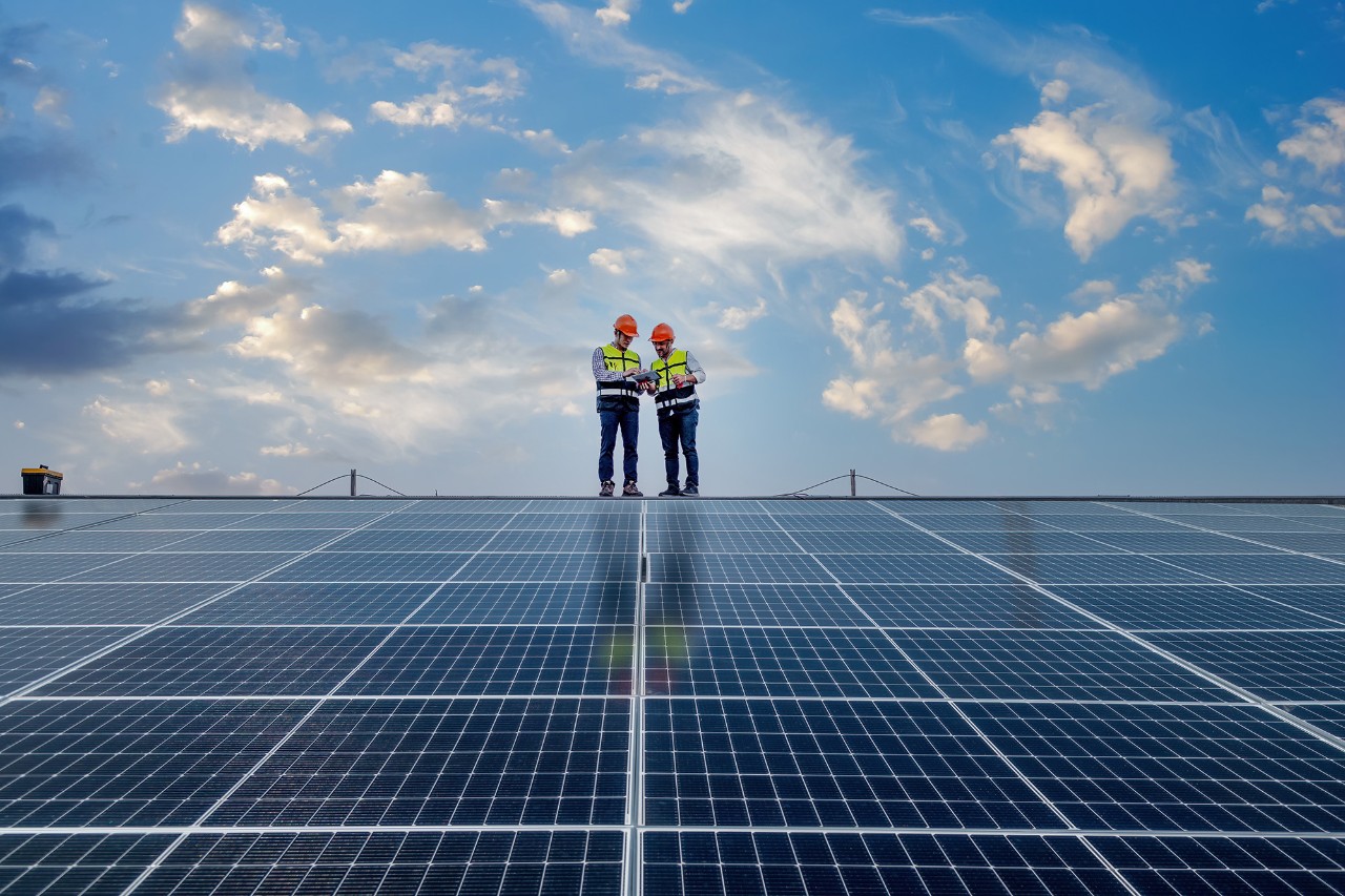 to elektrikere inspiserer taket på et fjøs med solceller