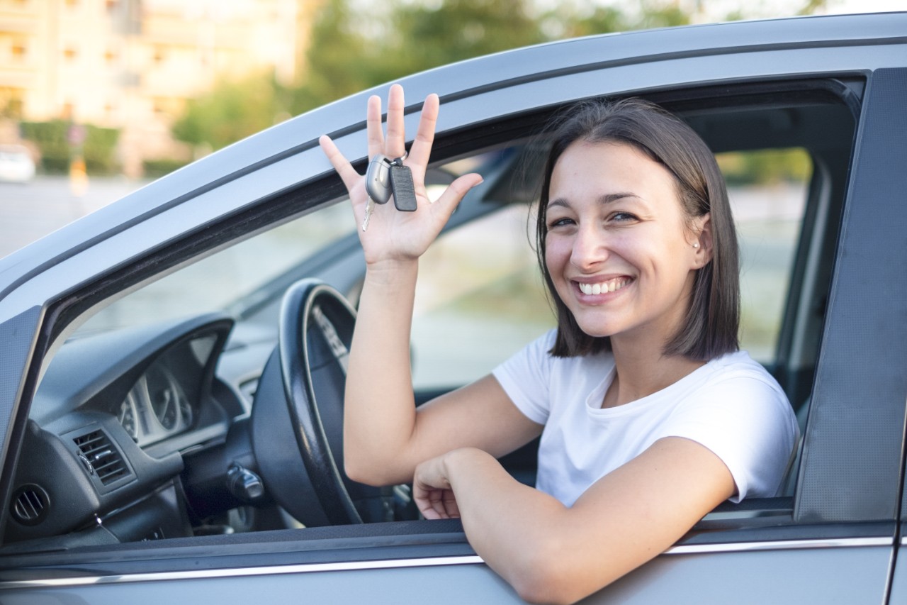 Happy smiling woman with car key ready to drive