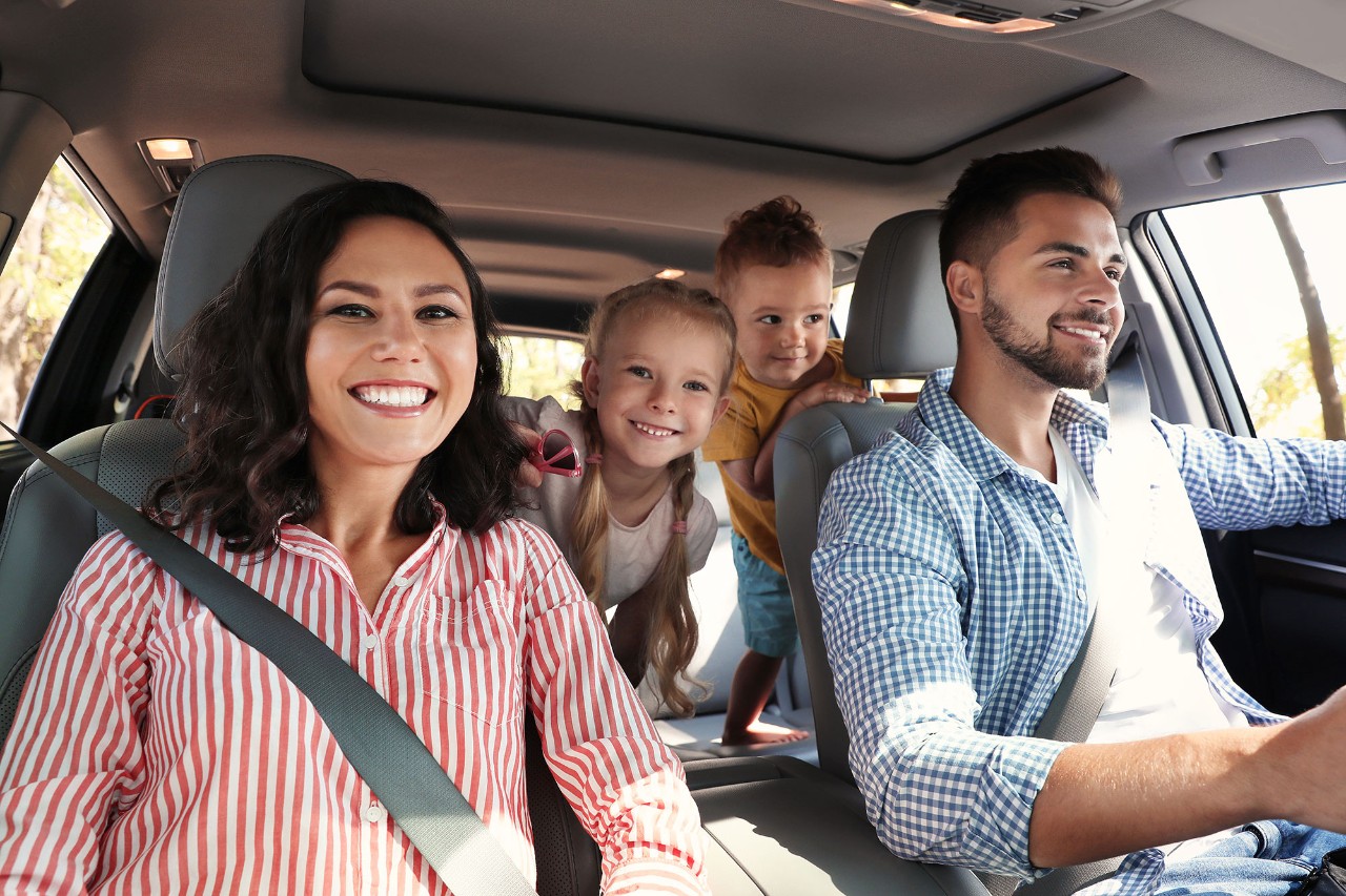glad familie i bil med bilforsikring med årlig kjørelengde på 12.000 km
