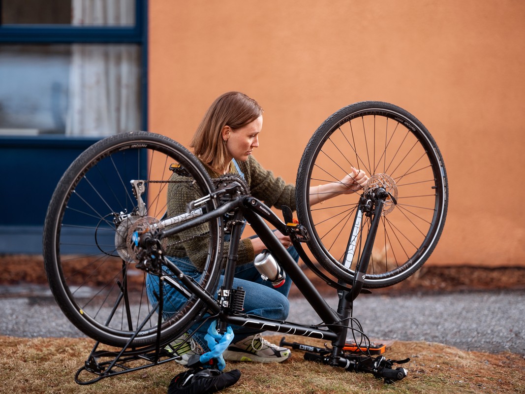 Damer sitter på huk ved sykkel of reparerer