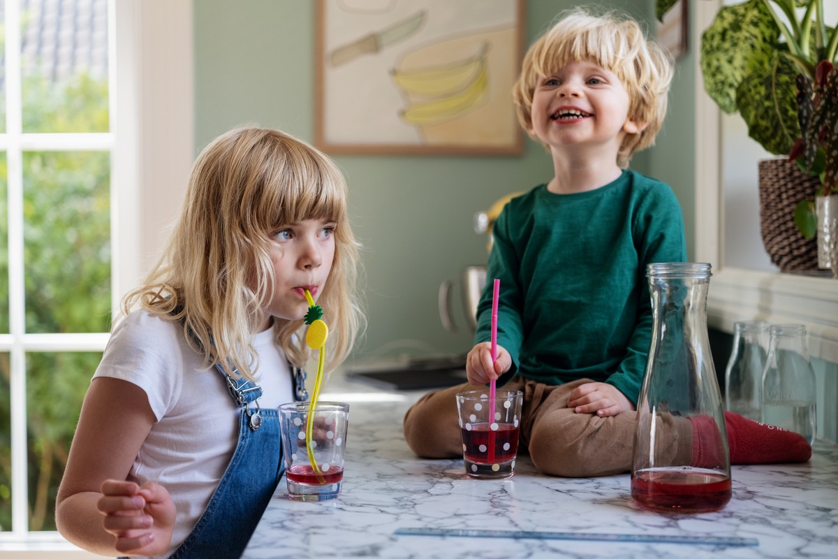 barn som drikker rød saft og smiler i en barnehage