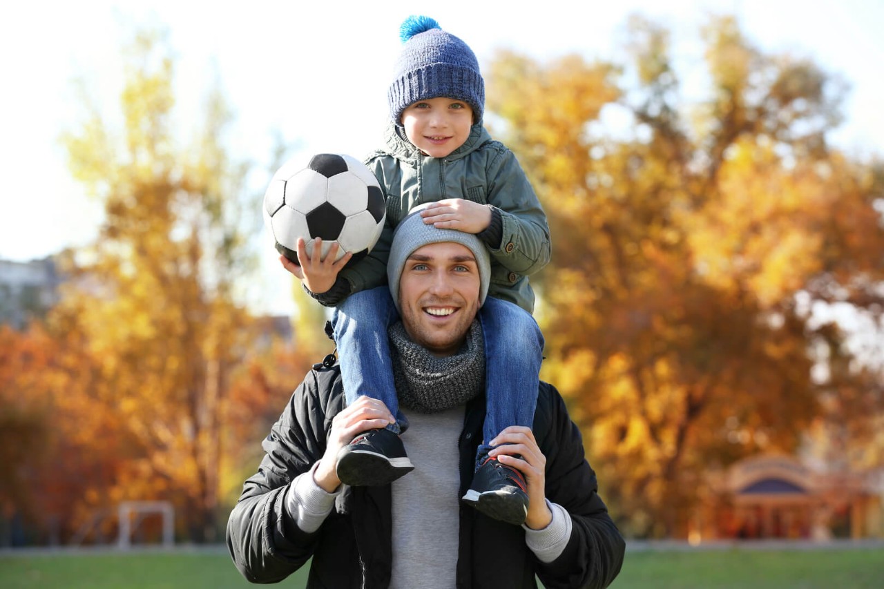 Far og barn med fotball, høst