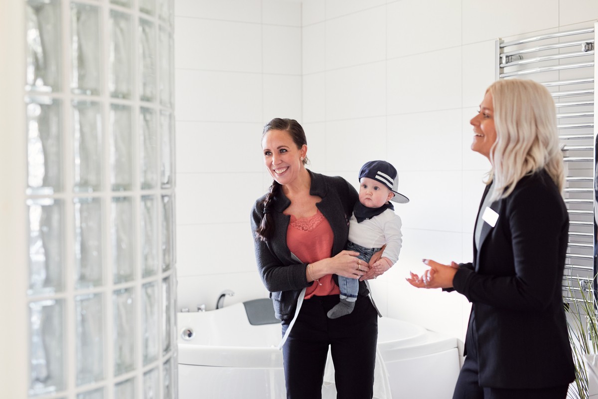 utleiemegler viser frem badet i en bolig til mamma med barn