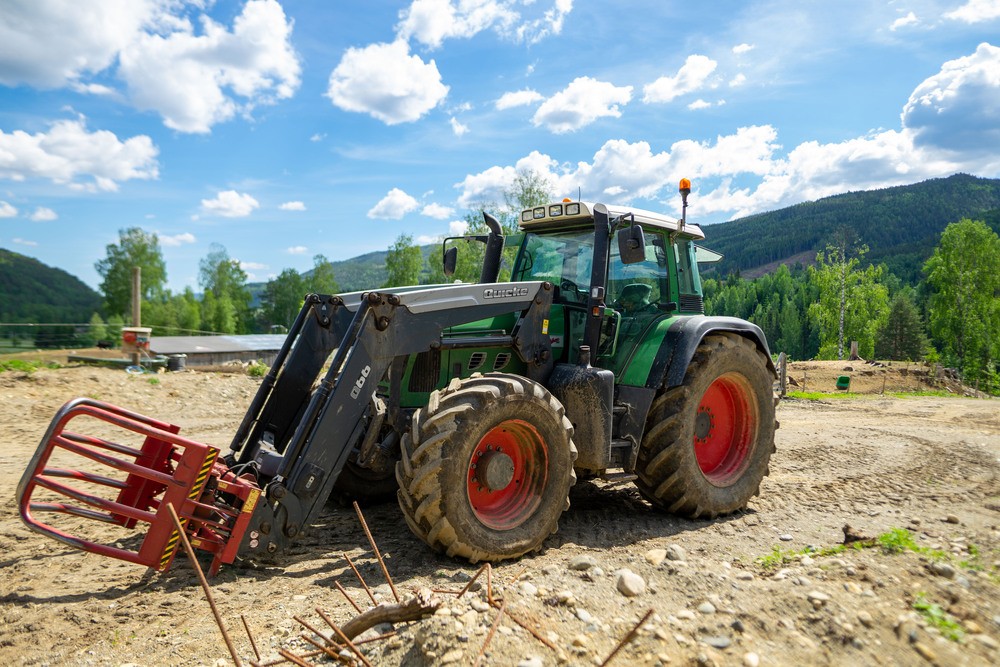 en fin og ny traktor med traktorforsikring står klar for en arbeidsøkt på et jorde