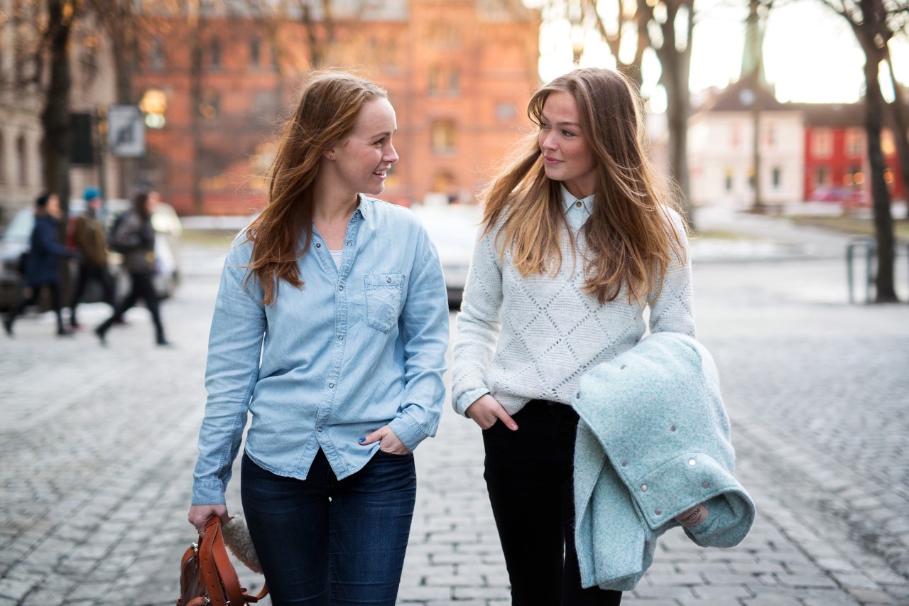 To jenter langs gata i by planlegger reise med reiseforsikring