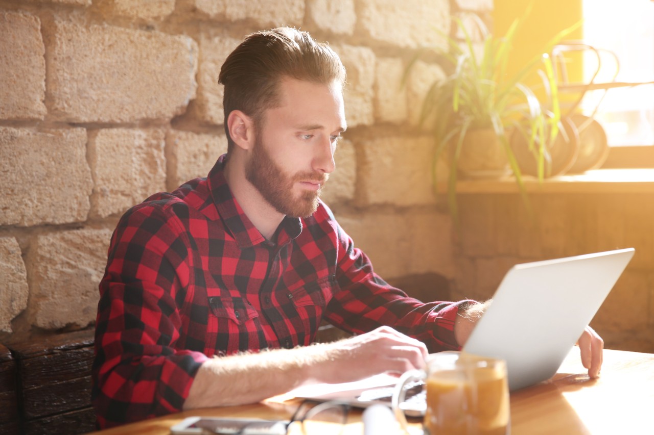 Man using laptop for browsing internet store at cafe. Online shopping concept