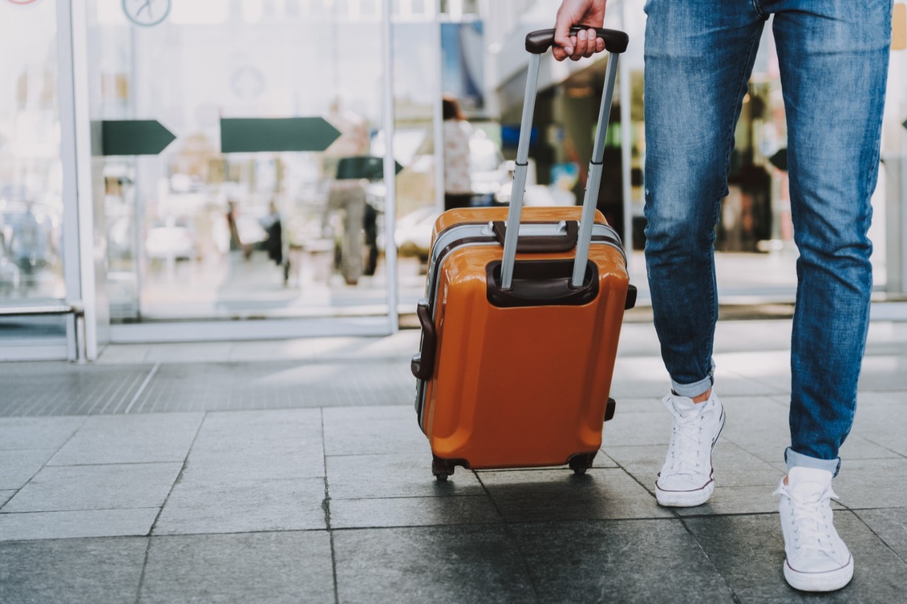 person med reisekoffert handler på taxfree på flyplassen