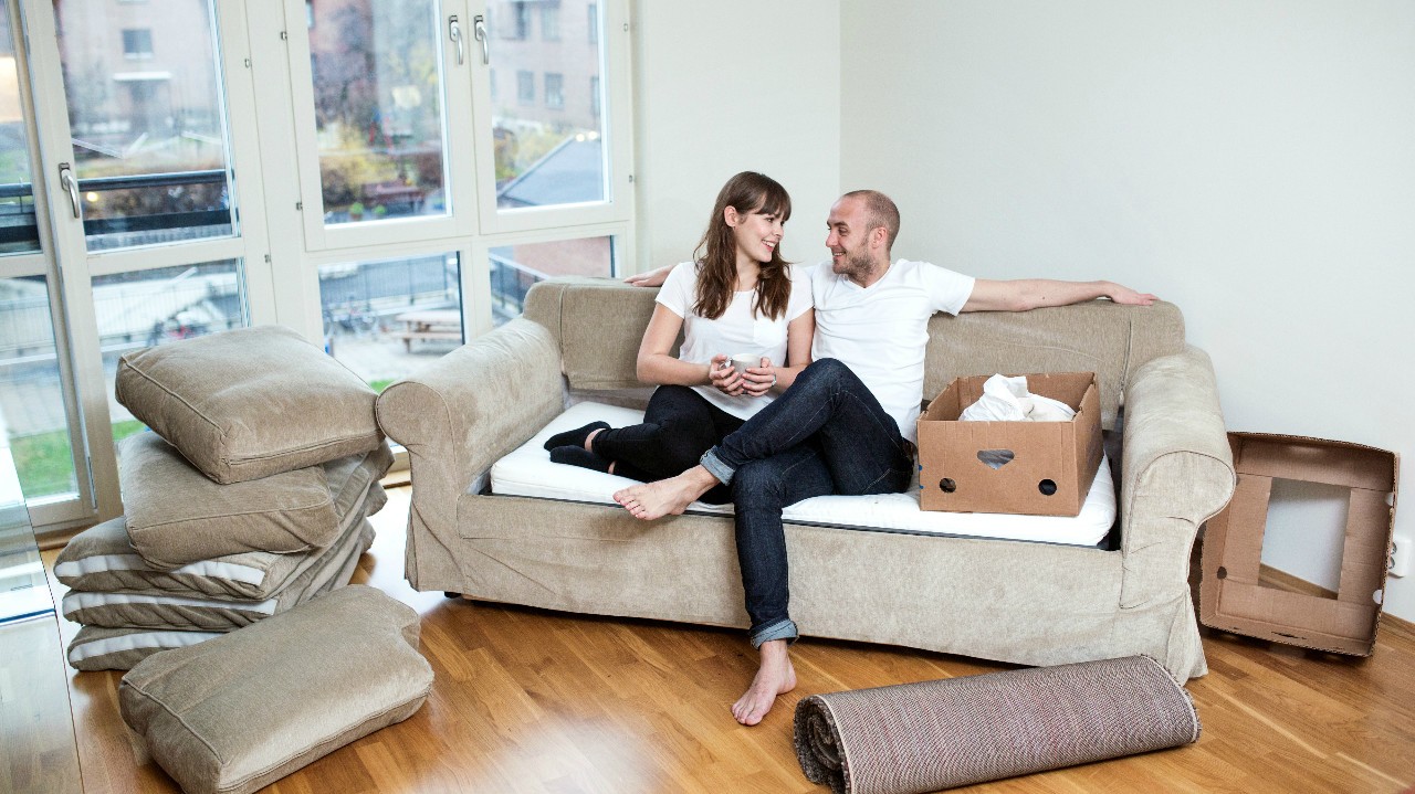 par med høy egenandel på innboforsikringen for å få lavere månedskostnader sitter i sofa etter flytting