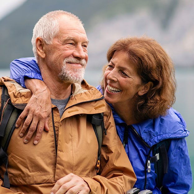 A senior pensioner couple hiking by lake in nature, resting.