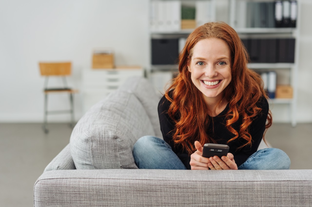 Photo of a young woman sitting on the floor and working on laptop